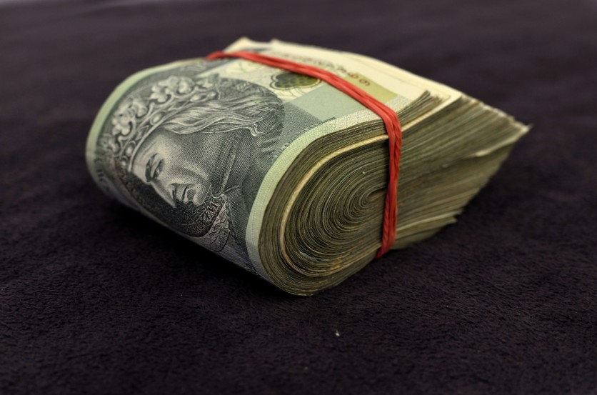 large folded stack of bills held with a red rubberband