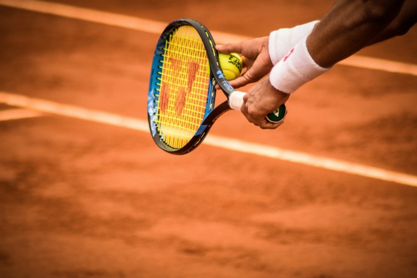 Tennis player preparing to serve on clay court