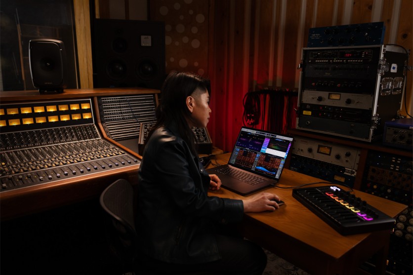 Producer working in Apple Music studio on laptop and mixing