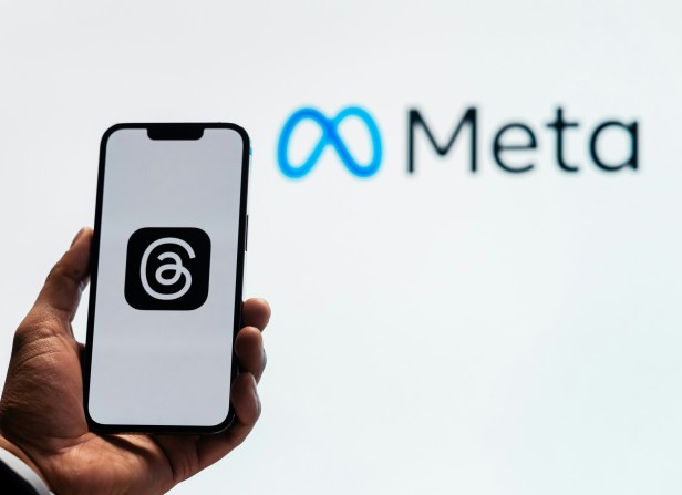 Threads app logo on phone held in front of Meta