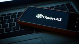 OpenAI logo on phone screen over laptop keyboard