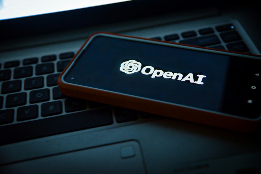 OpenAI logo on phone screen over laptop keyboard
