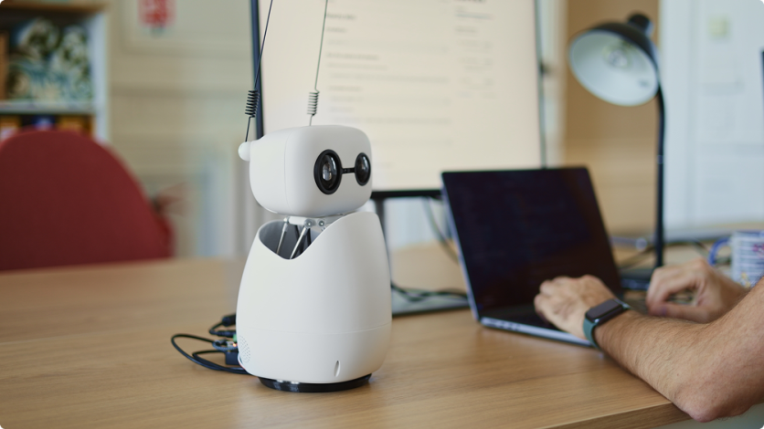 Small desktop robot with antennas beside laptop
