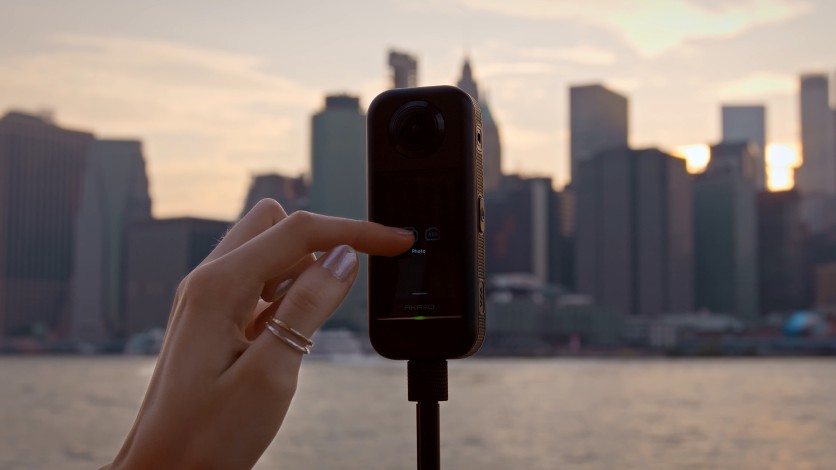 Hand interacting with AKASO 360 against city skyline