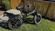 Black Engwe folding e-bike parked on grass in sunlight.