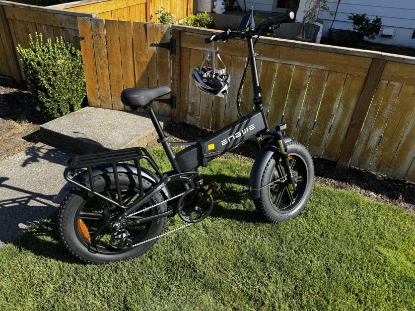 Black Engwe folding e-bike parked on grass in sunlight.