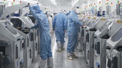 Technicians work on chip processing equipment at a semiconductor manufacturing