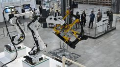Visitors look at industrial robots during a smart logistics demonstration