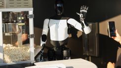 A Tesla Optimus robot scoops popcorn and waves at attendees