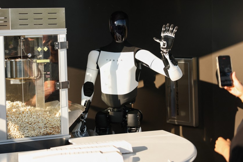 A Tesla Optimus robot scoops popcorn and waves at attendees