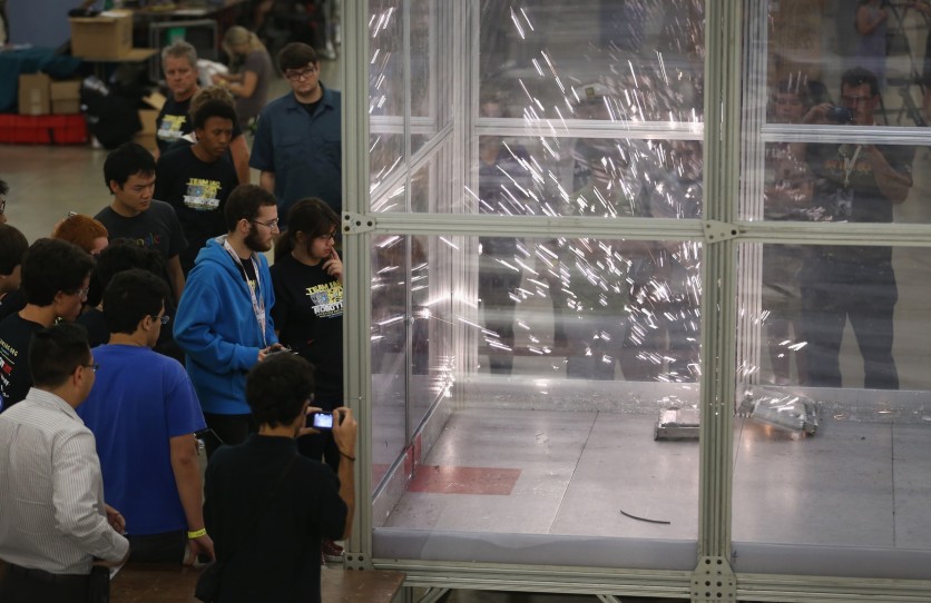 People watch as sparks fly from robots when they crash
