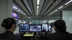 Health officials watch monitors showing whether incoming passengers have abnormal