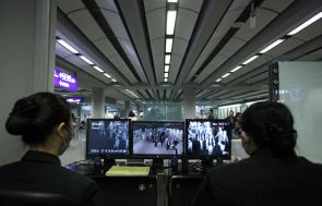 Health officials watch monitors showing whether incoming passengers have abnormal