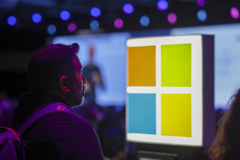 An audience member seated near a Microsoft logo listens as