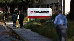 Pedestrians walk by a sign in front of a Broadcom