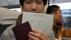 A Chinese student holds his passport and a ticket from