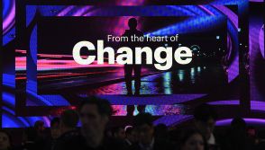 Visitors walk past a screen of Irish-American company Accenture, at