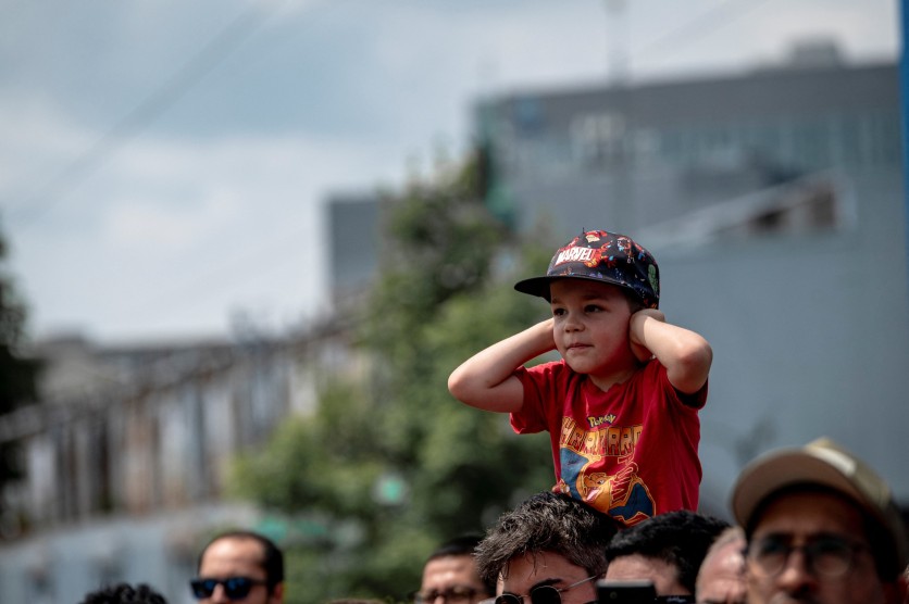 A boy covers his ears from the noise of cannons