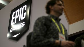 Attendees walk by the Epic Games booth at the 2019