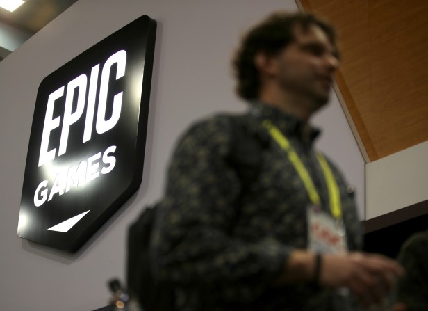 Attendees walk by the Epic Games booth at the 2019